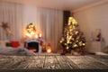 Empty wooden table in festively decorated room with Christmas tree near fireplace. Space for design Royalty Free Stock Photo