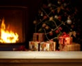 Empty wooden table over defocused Christmas background with Christmas tree, Gifts and fireplace; free space for your decoration Royalty Free Stock Photo