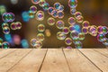 Empty wooden table or plank with bokeh of rainbow soap bubbles from the bubble blower on background. Royalty Free Stock Photo