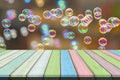 Empty wooden table or plank with bokeh of rainbow soap bubbles from the bubble blower on background. Royalty Free Stock Photo