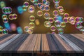 Empty wooden table or plank with bokeh of rainbow soap bubbles from the bubble blower on background for product display. Royalty Free Stock Photo