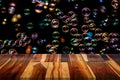 Empty wooden table or plank with bokeh of rainbow soap bubbles from the bubble blower. Royalty Free Stock Photo