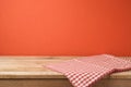 Empty wooden table with red checked tablecloth over red wall background