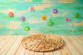 Empty wooden table with round wicker placemat over colorful background