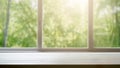 Empty wooden table sits before a window revealing a dense forest. Sunlight casts patterns on the table.