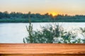 Empty wooden table with summer background of riverside at sunset. Can be used for display or montage product