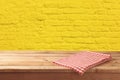 Empty wooden table with tablecloth over yellow brick stone wall background Royalty Free Stock Photo