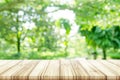 Empty wooden table top with blurred green natural background.