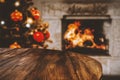 Empty wooden table top and christmas tree, home interior with fireplace and dark wall background. Empty space for your products. Royalty Free Stock Photo