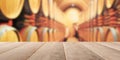 Empty wooden table top with out of focus wine cellar background with wooden wine barrels Royalty Free Stock Photo