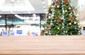 Empty wooden table top over Defocused of decorated Christmas tree with toys, gift box, lights, bauble inside the office building. Royalty Free Stock Photo