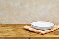 Empty wooden table with white plate above tablecloth over grunge background Royalty Free Stock Photo