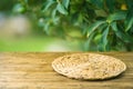 Empty wooden table with wicker round placemat over green garden blurred background. Spring mock up for design