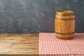 Empty wooden table with wine barrel and tablecloth over black wall background