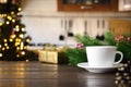 Empty wooden tabletop with cup of coffee and blurred modern kitchen with Christmas tree Royalty Free Stock Photo