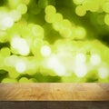 Empty wooden top table and bright blurred green background with lights and bokeh, focus on tabletop