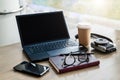 Empty workplace. Near window on desk is laptop, smartphone, notebook, glasses, cup of coffee, camera for instant photos. Royalty Free Stock Photo