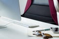 Empty workplace of a young female business woman. Bright and white minimalistic desk with desktop computer, smartphone and a note