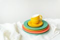 Empty yellow cups and brightly colored plates on a white table covered with a linen tablecloth Royalty Free Stock Photo