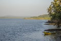 A empty yellow fishing boat on the bank of the river against the backdrop of green palm trees and hills Royalty Free Stock Photo