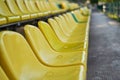 Empty yellow and green plastic seats on stands of stadium in open. Royalty Free Stock Photo