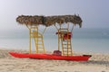 Empty yellow lifeguard towers with palm thatch roof and bright red kayak on a foggy day at deserted beach Royalty Free Stock Photo