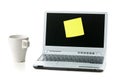 Empty yellow sticky paper note on laptop with cup of coffee with copy space over white Royalty Free Stock Photo