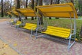 Empty yellow swing benches in a city park, garden or near a playground