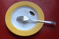 Empty yellow used plate with fork, breadcrumbs and a small bay leaf Royalty Free Stock Photo