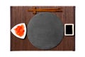 Emptyround black slate plate with chopsticks for sushi, ginger and soy sauce on dark bamboo mat background. Top view with copy Royalty Free Stock Photo