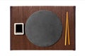 Emptyround black slate plate with chopsticks for sushi and soy sauce on dark bamboo mat background. Top view with copy space for Royalty Free Stock Photo