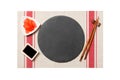 Emptyround black slate plate with chopsticks for sushi and soy sauce, ginger on sushi mat background. Top view with copy space for Royalty Free Stock Photo