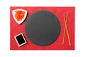 Emptyround black slate plate with chopsticks for sushi and soy sauce, ginger on red mat sushi background. Top view with copy space Royalty Free Stock Photo