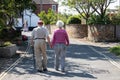 An elderly couple taking a walk holding hands