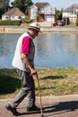 An elderly man taking a walk using a cane or walking stick