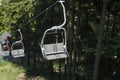 Emtpy double chair lift ride in sunny summer day. travel concept. backdrop of a dense forest. Mountains and hills in Summer with