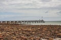 Stones scattered at the shore of Emu Bay with historic jetty during cast cloudy sky on Kangaroo Island in Australia. a Royalty Free Stock Photo