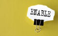 ENABLE- the word is printed on a white piece of paper on a yellow background