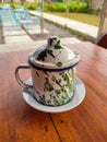 An old-fashioned green patterned white enamel cup