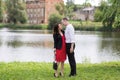 Enamored man and woman stand on fresh green grass on the river bank