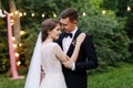 Enamored newlyweds gentle embrace. Wedding ceremony in nature. The lights of the electric garland illuminate the wedding