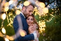 Enamored newlyweds gently embrace. Wedding ceremony in nature. The lights of the electric garland illuminate the wedding