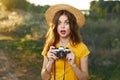 Enamored woman holding a camera in her hands hat red lips yellow t-shirt fresh air