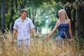 Enamoured young man and girl walk on high grass