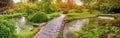Enchanted eden garden bridge over pond in horizontal panoramic Nymph Garden or Giardino della Ninfa in Lazio - Italy