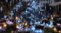 Enchanted Forest Dinner Table with Glowing Decorations and White Flowers Under Moody Lighting, Trees With Glowing String Lights Royalty Free Stock Photo