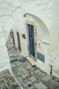Discover the Hidden Charm of Ostuni\'s Historical White Alleyway Through a Medieval Archway with Stunning Blue Door View