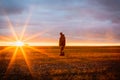 Enchanting sunrise, one male farmer in a field at dawn on the horizon against the backdrop of the rising sun with rays in the