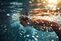 Underwater shot of a young woman swimming in the pool with goggles at sunset
