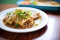 enchiladas smothered in chili con carne and onions